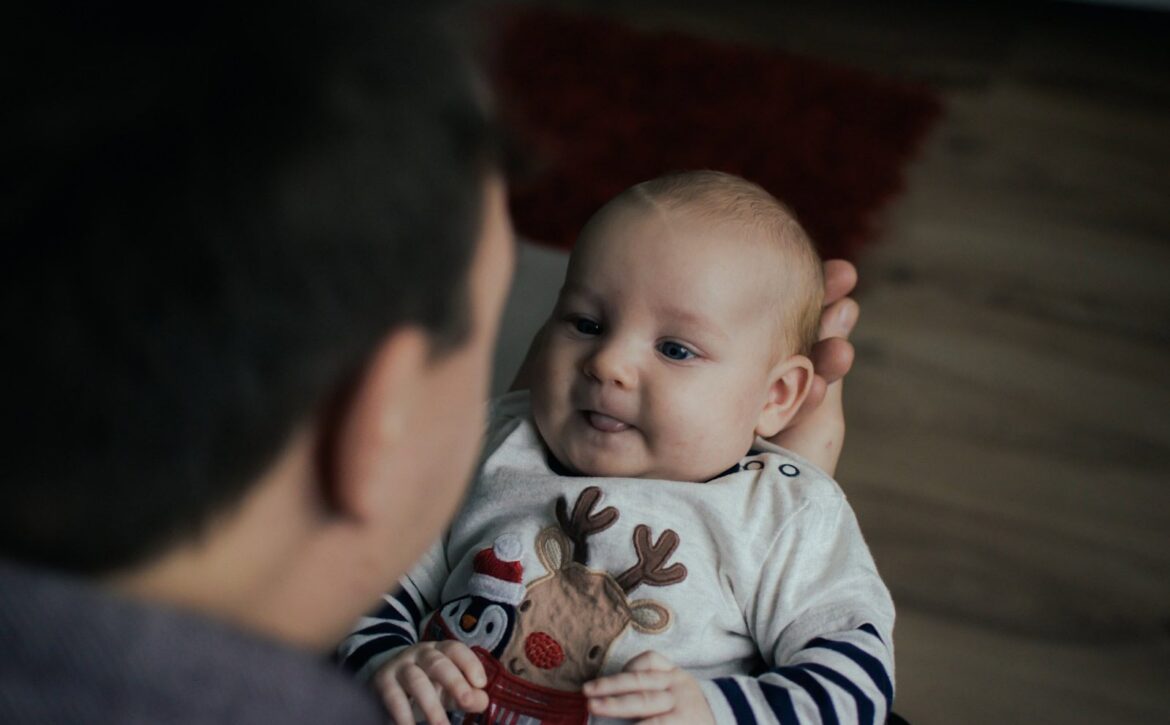 An adult holding a baby while they face one another.