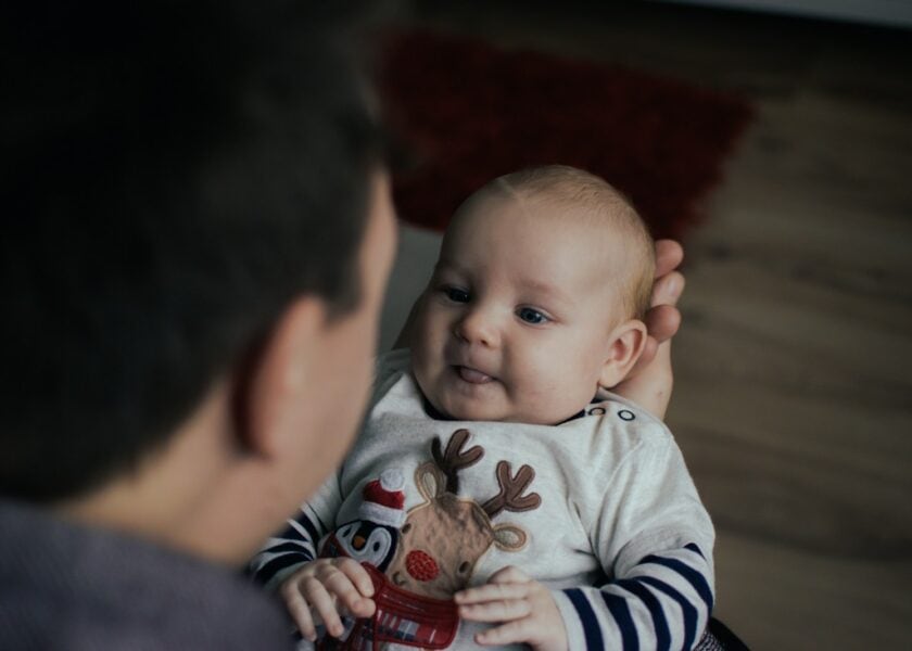 An adult holding a baby while they face one another.