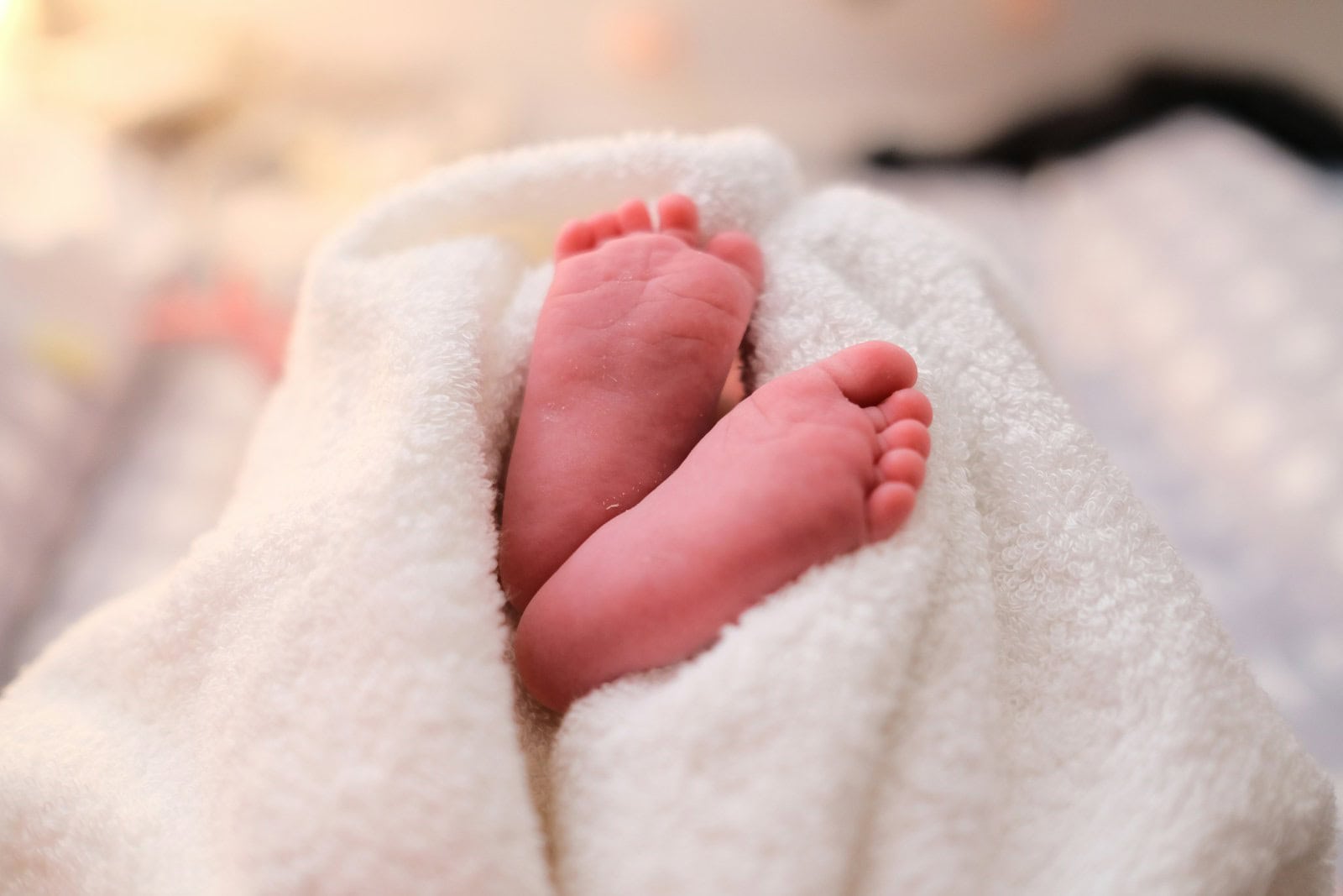 A close-up of a baby's bare feet resting against a white blanket.
