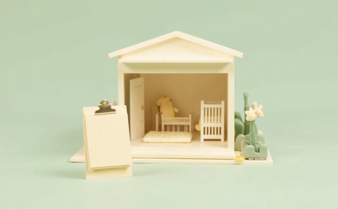 A stylised ivory miniature care room with two cots, a teddy bear, blank clipboard and small plants against mint green.