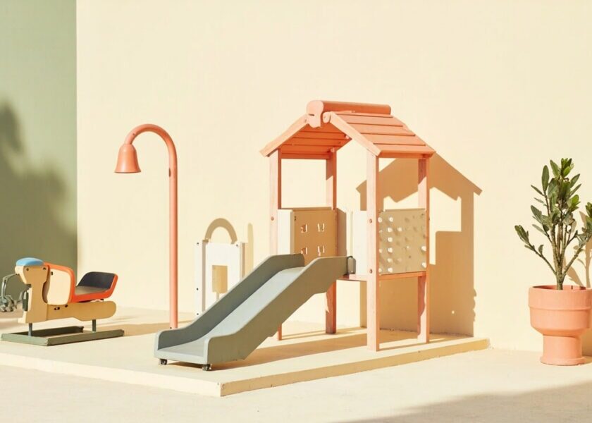 A stylised, empty play area with a low slide, climbing frame, spring rider, curved lamp and potted plants.