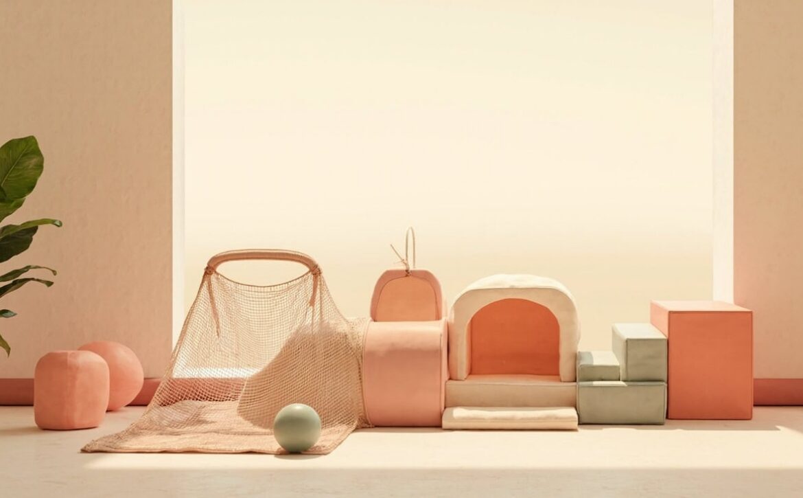 Soft coral-and-cream foam tunnel, open play net and blocks with a small sage ball in a warm, uncluttered interior.