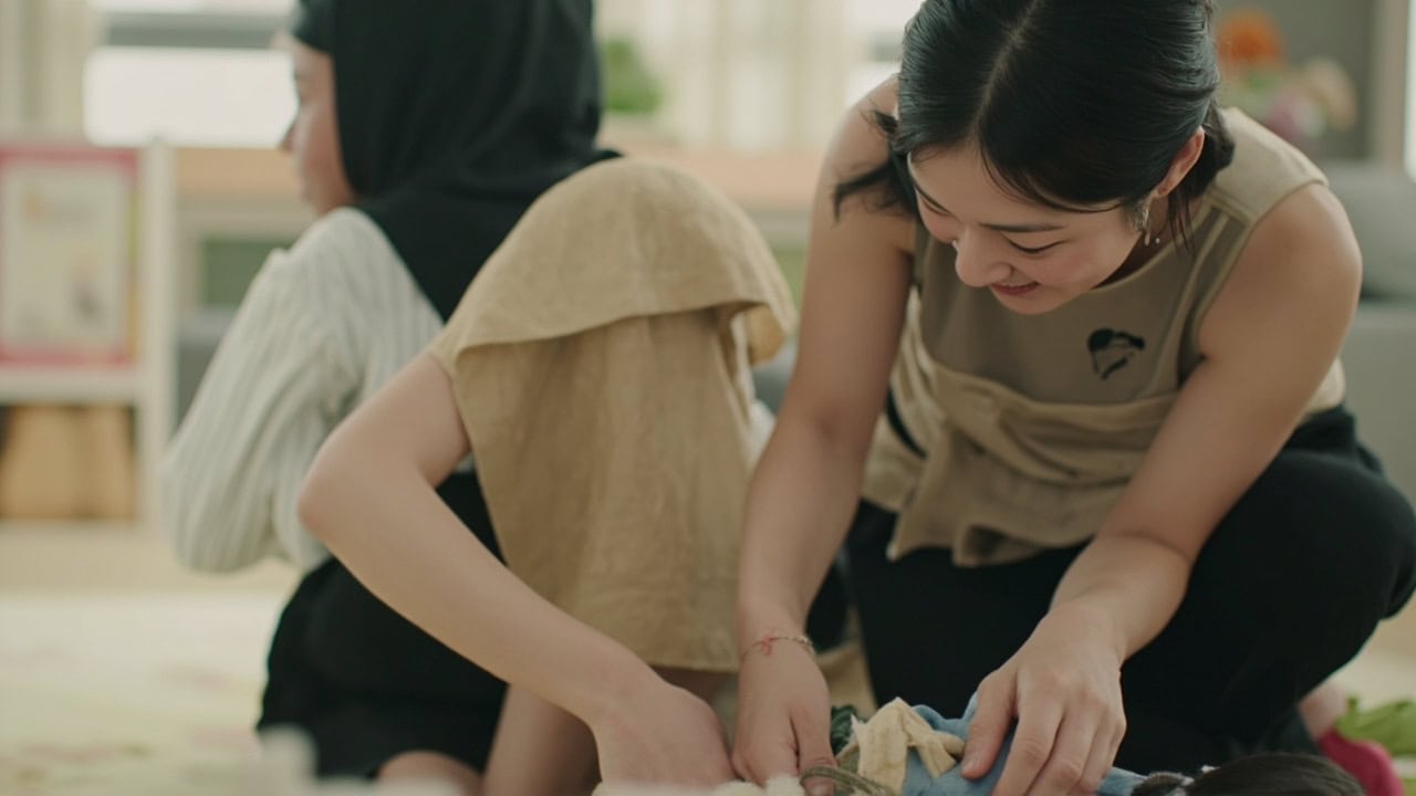 Close view of a childminder placing a stable cloth object within an infant’s view.