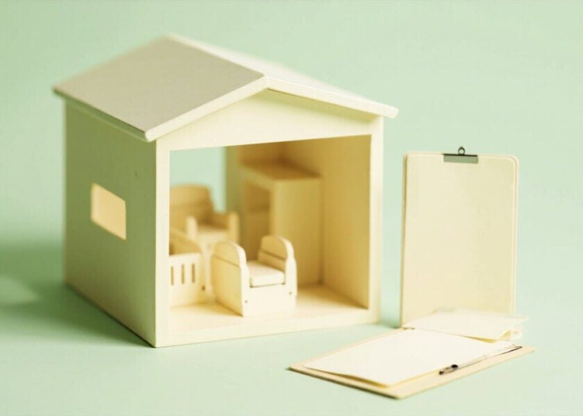 A minimalist model care room with small chairs and blank paperwork beside it in warm ivory and muted green.