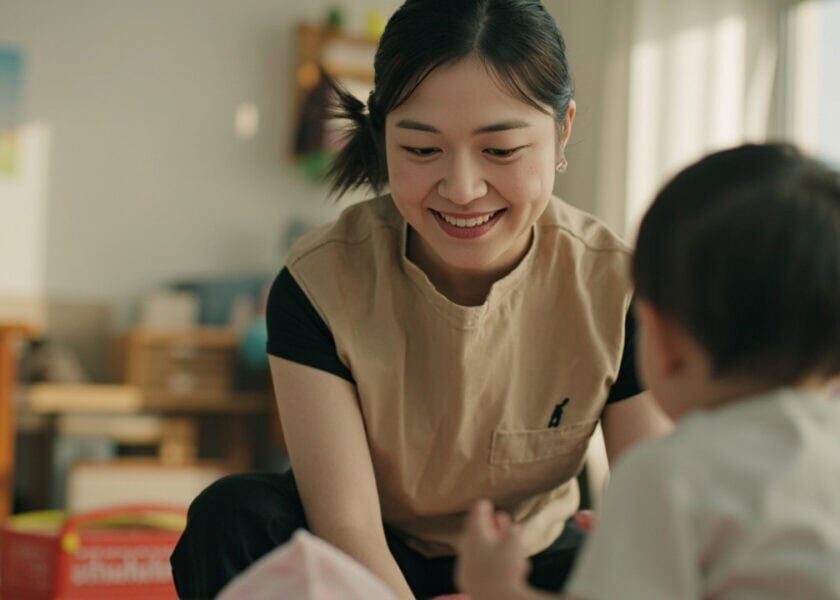 AI illustration of a uniformed childminder giving responsive care to three awake infants in a bright Singapore home playroom