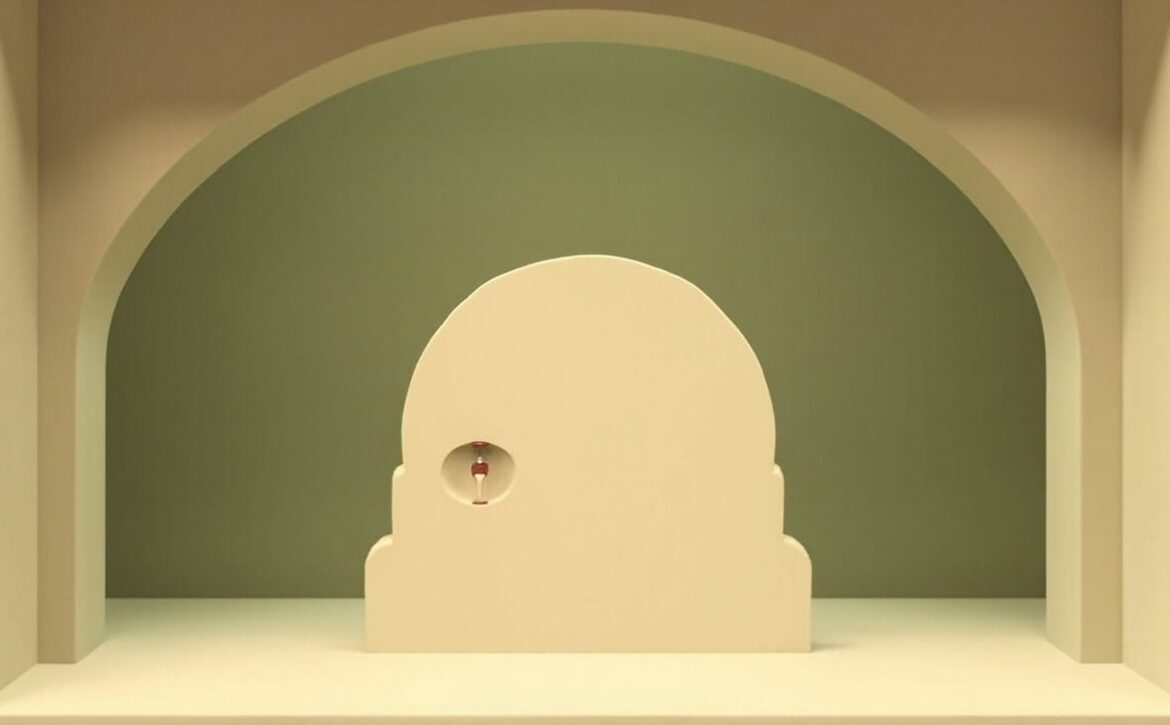 Stylised cream vault-like doorway in an olive-green alcove, with a small unmarked hourglass inside its round handle.