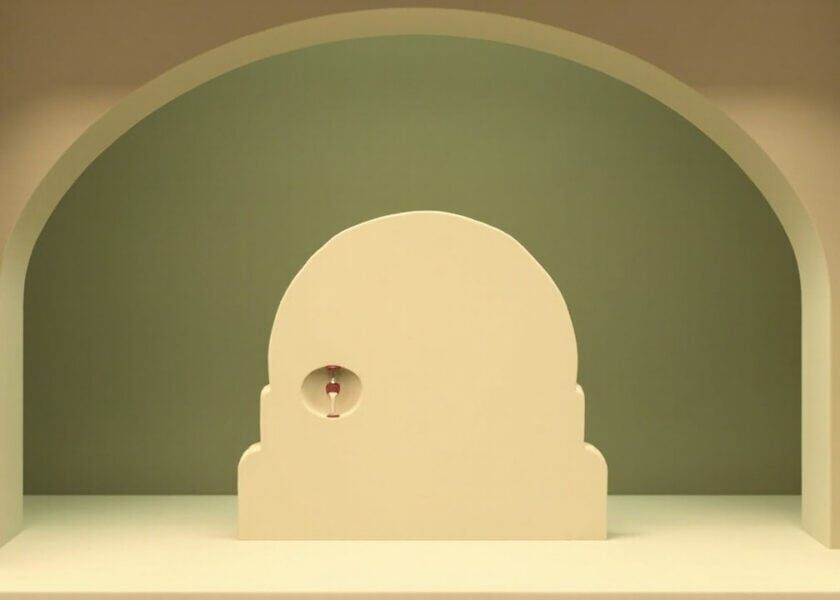 Stylised cream vault-like doorway in an olive-green alcove, with a small unmarked hourglass inside its round handle.