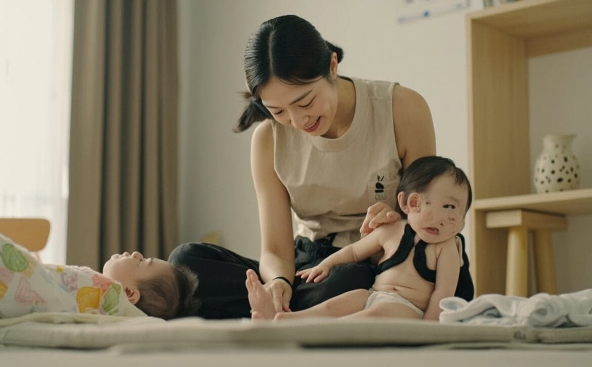 Childminder acknowledges two infants during shared floor play